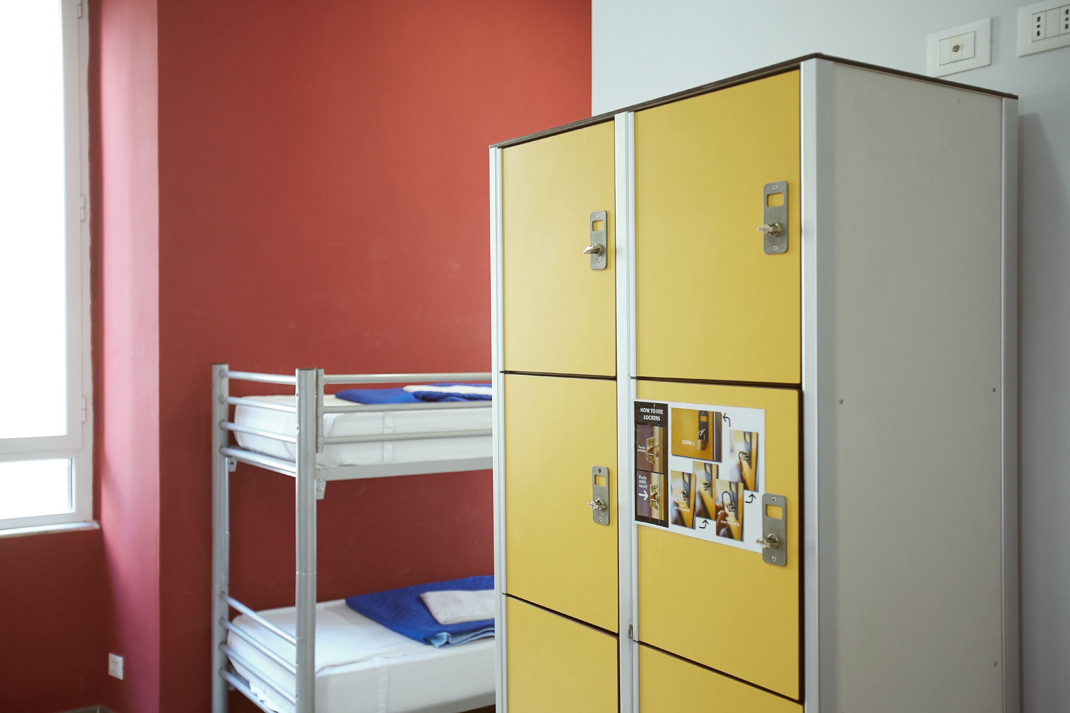 Een stapelbed met een blauwe matras en een gele kast met een poster erop.