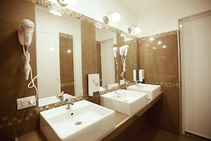 A bathroom with three sinks, a hairdryer, and a mirror. - Alessandro Palace & Bar - Hostel (Rome)