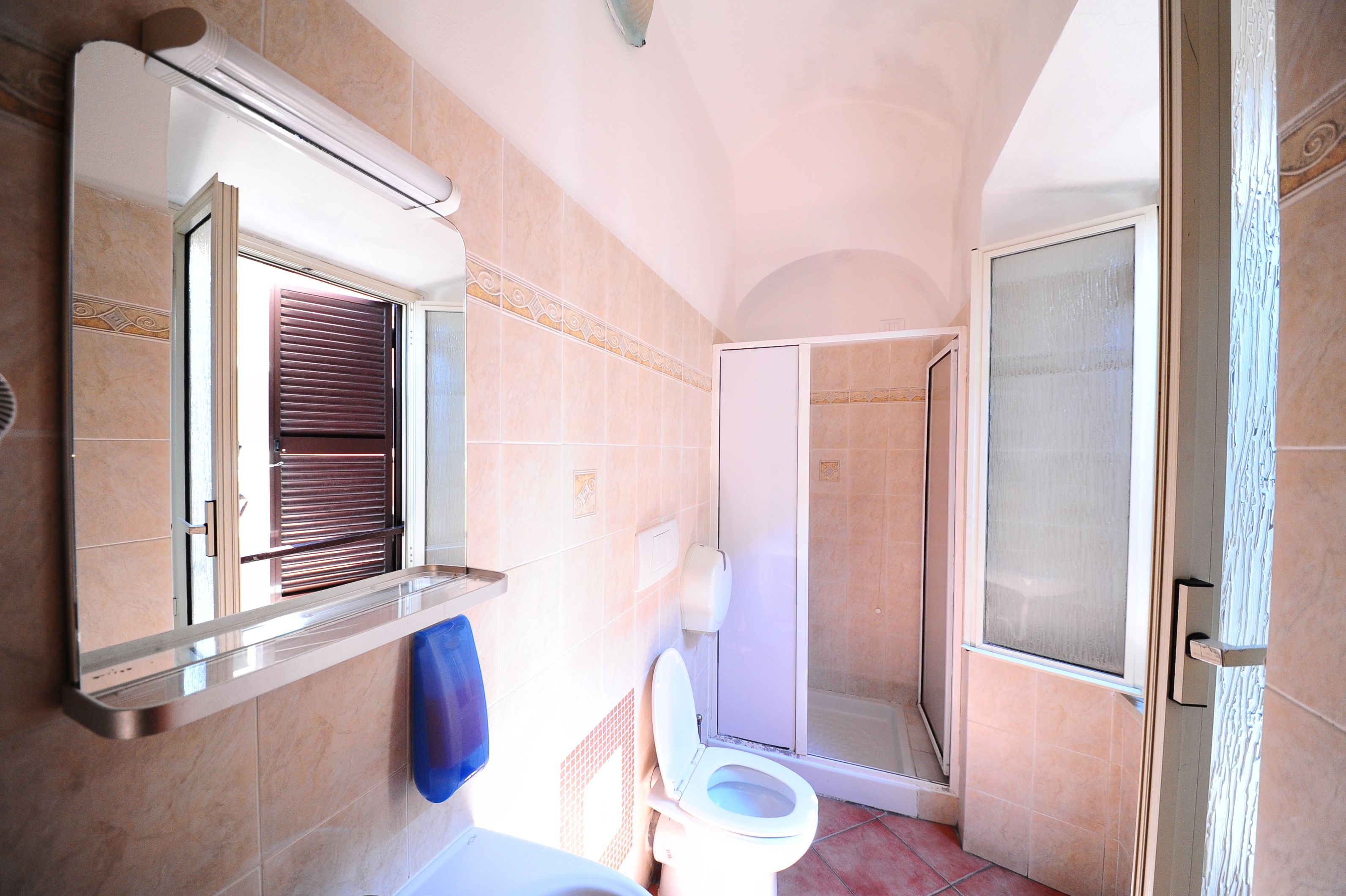 Un baño con inodoro, ducha y puerta de vidrio que da acceso a la zona de ducha.
