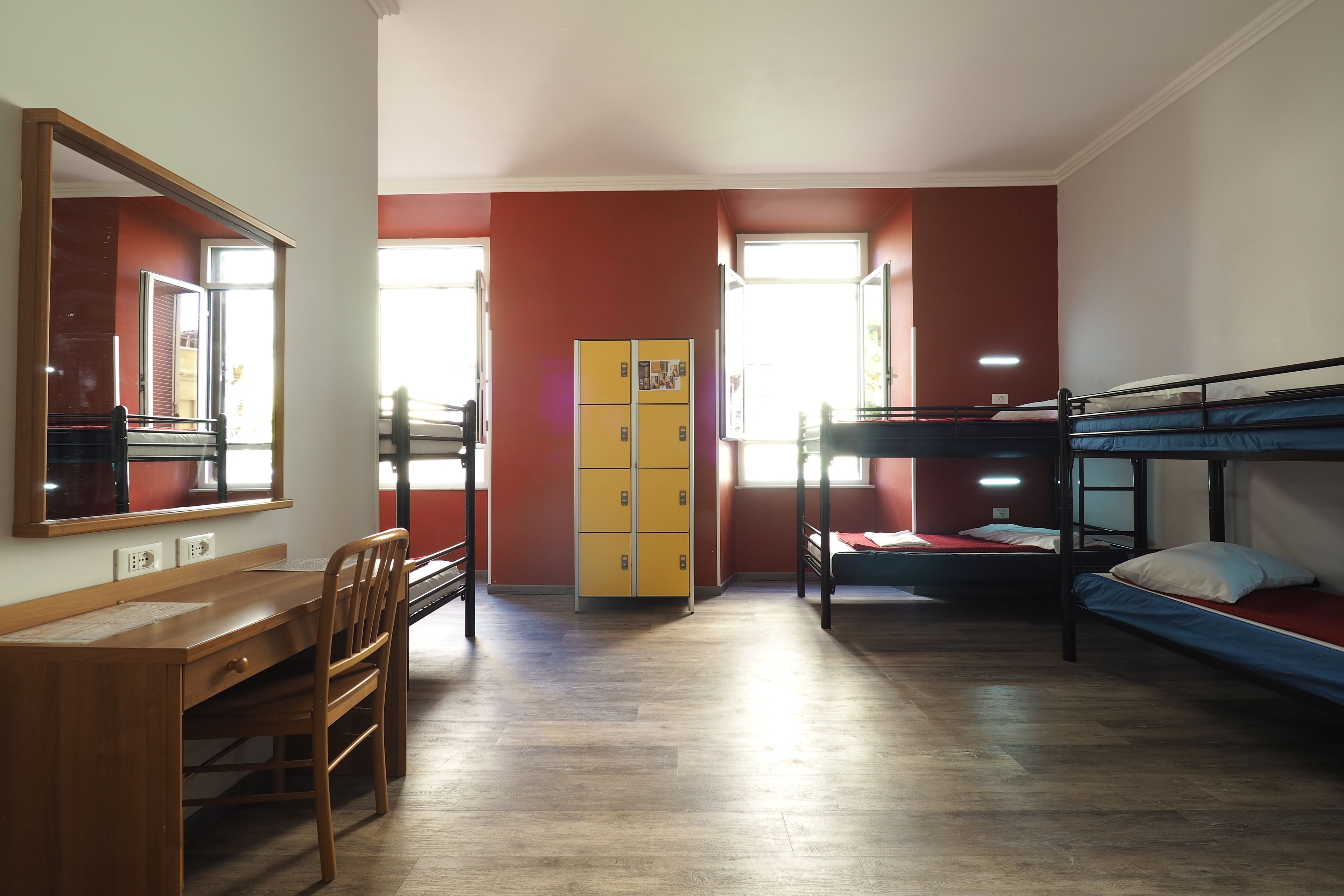 Une chambre de dortoir équipée de lits superposés, d’un bureau, d’une chaise, d’une armoire et d’un miroir.