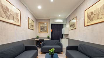 Et moderne værelse med to sofaer, et lille bord med en plante, et skrivebord og en stol.