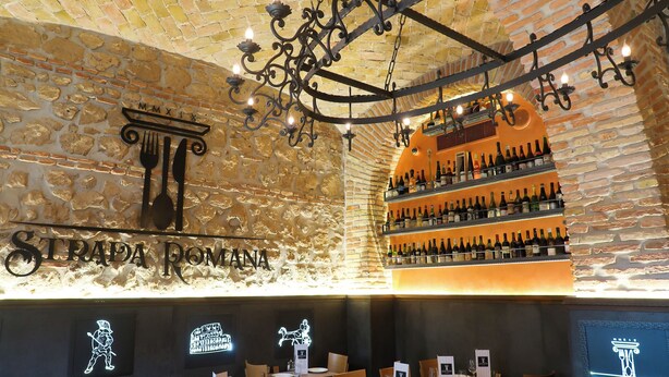 A restaurant interior with a brick wall, a chandelier, and a wine rack. - Alessandro Palace & Bar - Hostel (Rome)