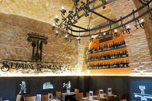 L’intérieur d’un restaurant avec un mur en briques, un lustre et un meuble à bouteilles de vin.