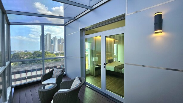 A balcony with wicker chairs and a view of the cityscape.