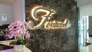 A reception area with a marble wall, a 'Free Wireless Internet' sign, and a floral arrangement.