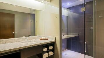 Un baño moderno con un espejo grande, lavamanos dobles y una zona de ducha con mampara de vidrio.