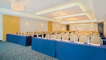 A conference room with rows of tables, chairs, and a chandelier.
