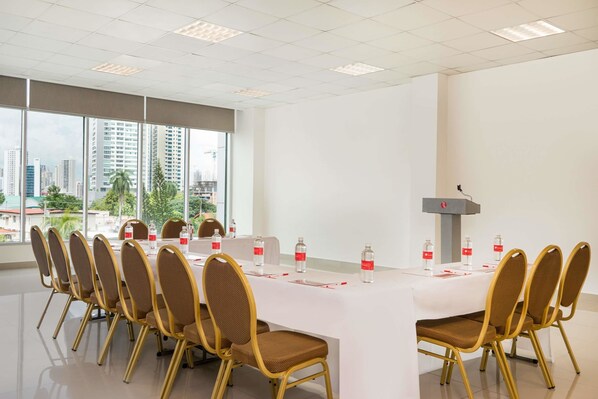 Un salón de conferencias con una mesa larga, sillas y un atril.