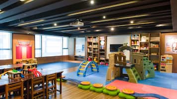 Kids can play and learn in this play area with a climbing arch, slide, and castle, featuring safety mats and seating areas.