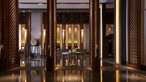 Un moderno vestíbulo con piso reflectante, un área central de asientos y paneles decorativos de madera.