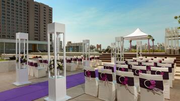 A wedding ceremony setup with white chairs, purple sashes, and a white tent.