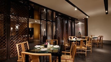 A dining area with wooden chairs and tables, a decorative screen, and a modern interior design.