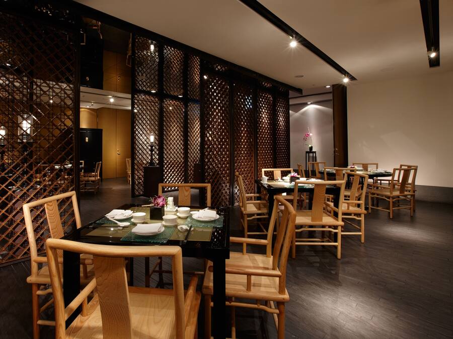 A dining area with wooden chairs and tables, a decorative screen, and a modern interior design.
