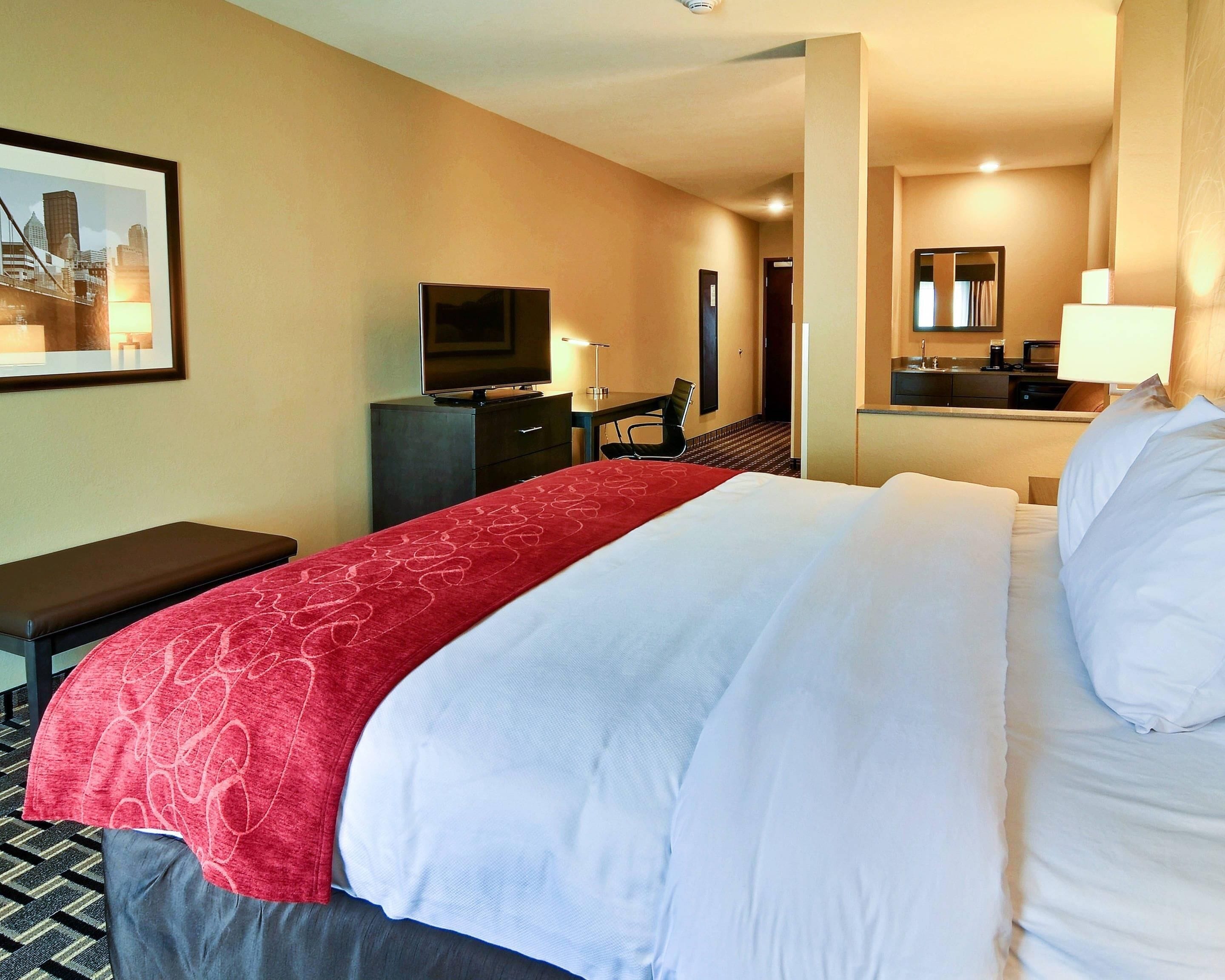 Ein Hotelzimmer mit Bett, Schreibtisch, Fernseher, Spiegel und Bad.