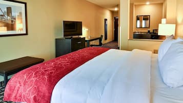 A hotel room with a bed, a desk, a television, a mirror, and a bathroom.