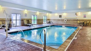 Ein Hallenbad mit klarem Wasser, einer Rettungswache und Liegestühlen.