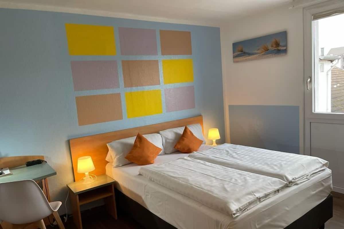 Une chambre d’hôtel comprenant un lit, deux tables de chevet avec des lampes, un bureau et une chaise.