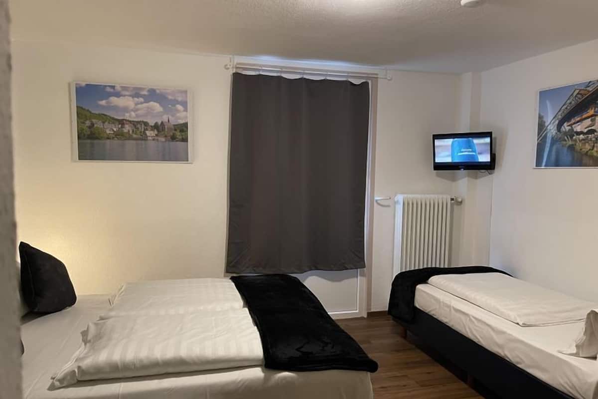 Une chambre d’hôtel avec deux lits, une télévision et une fenêtre avec des rideaux.