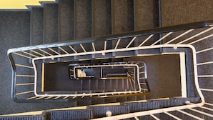 Un escalier en colimaçon avec une rampe métallique et des marches en bois.