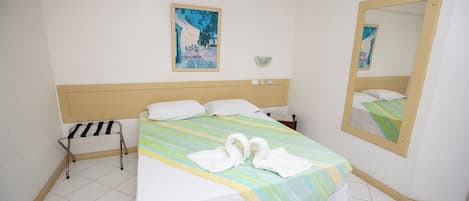 Habitación de hotel con una cama, una mesita de noche, un espejo y un aire acondicionado instalado en la pared.