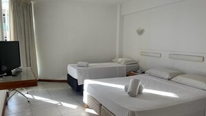 Een hotelkamer met twee bedden, een bureau met een computer en een raam met gordijnen.