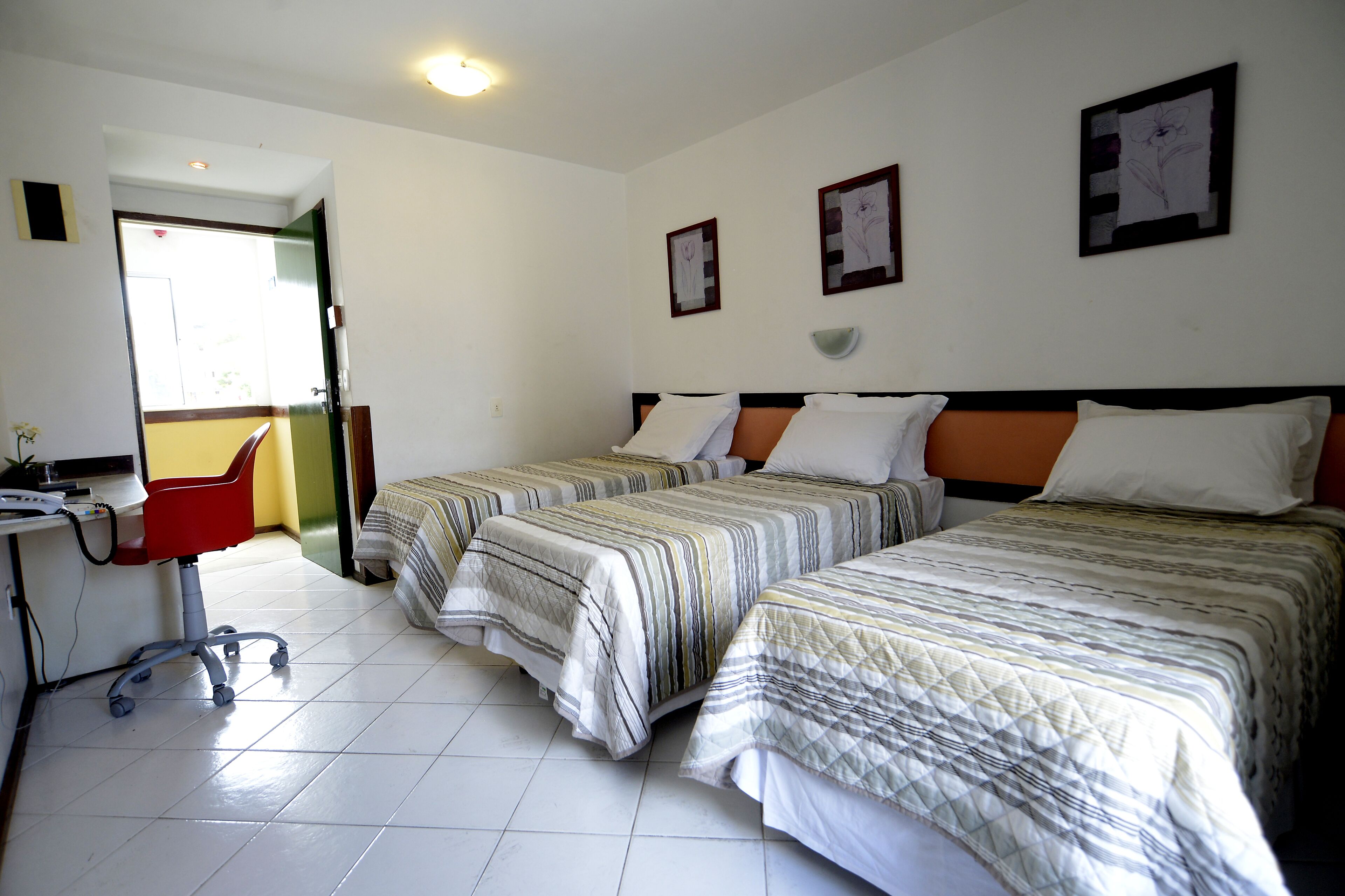 A hotel room with two beds, a desk, and a chair.
