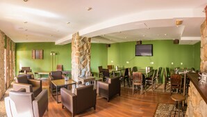 Een restaurant met groene wanden, een stenen zuil, een houten bar en leren stoelen.