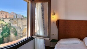 Een hotelkamer met een groot raam met uitzicht op een historische stenen brug en gebouwen.
