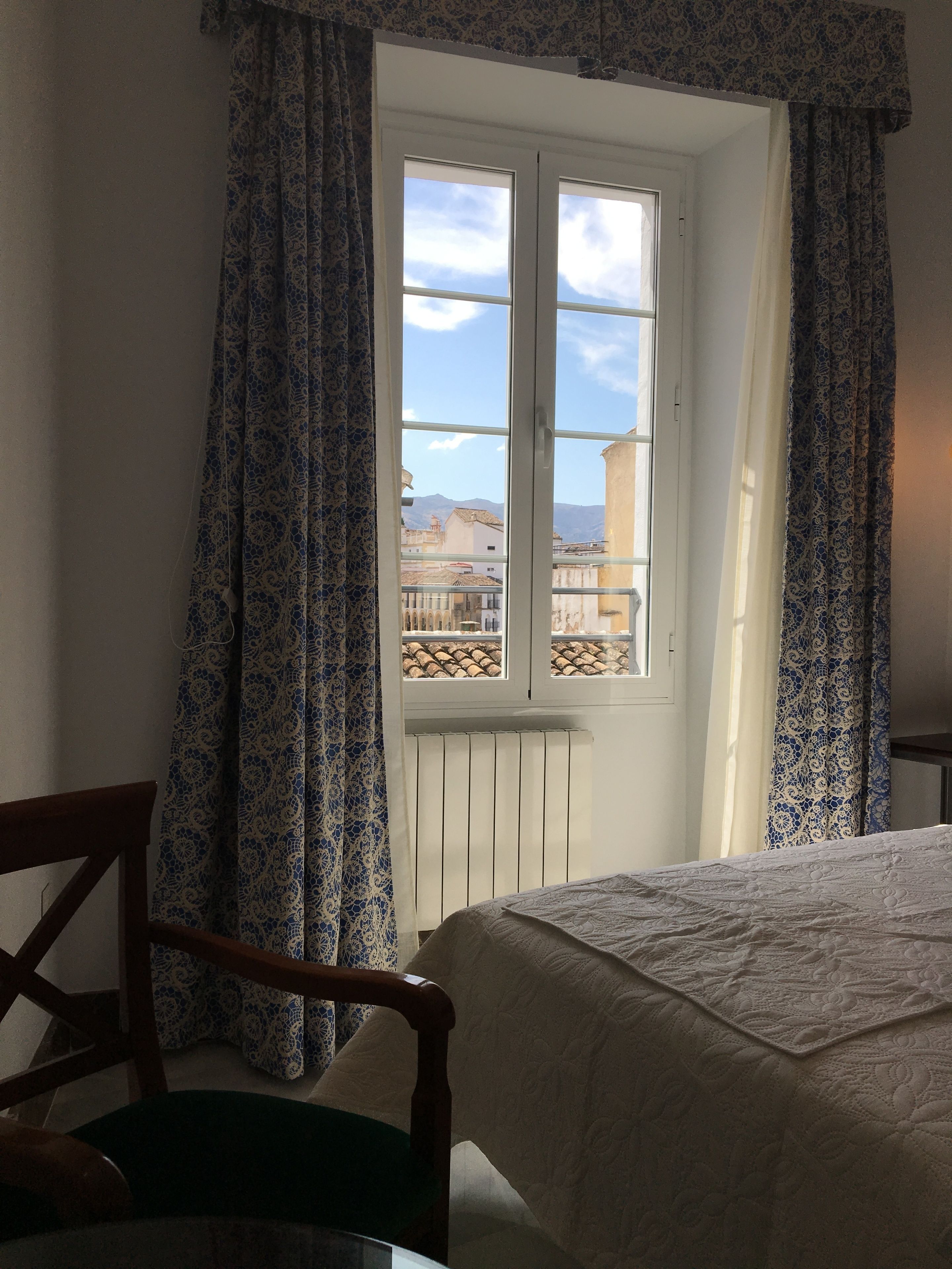 A bedroom with a window, a bed, and a chair.