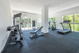 Un gimnasio moderno con cintas de correr, mancuernas y bancos de pesas.