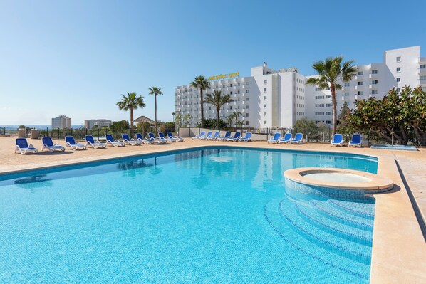 A swimming pool with blue tiles, surrounded by lounge chairs and palm trees. - Hotel HSM Canarios Park - All Inclusive (Manacor)