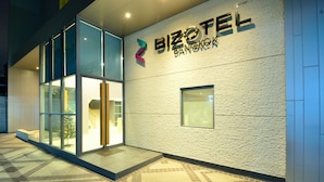 Um edifício moderno com fachada de vidro e uma placa que diz "BIZOTEL Bangkok".
