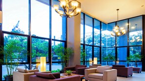 A spacious lobby with large windows, modern furniture, and a chandelier.