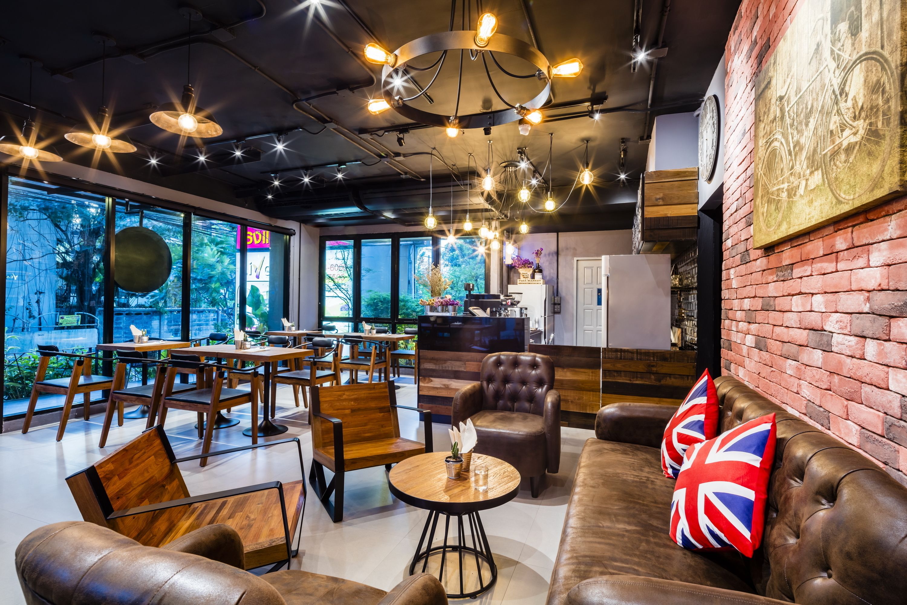 A modern cafe with wooden furniture, leather seating, and a brick wall.