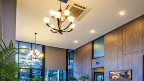 A spacious lobby with modern furniture, large windows, and a chandelier.