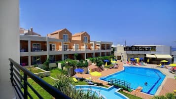 A hotel with a swimming pool, multiple balconies, and outdoor seating areas.