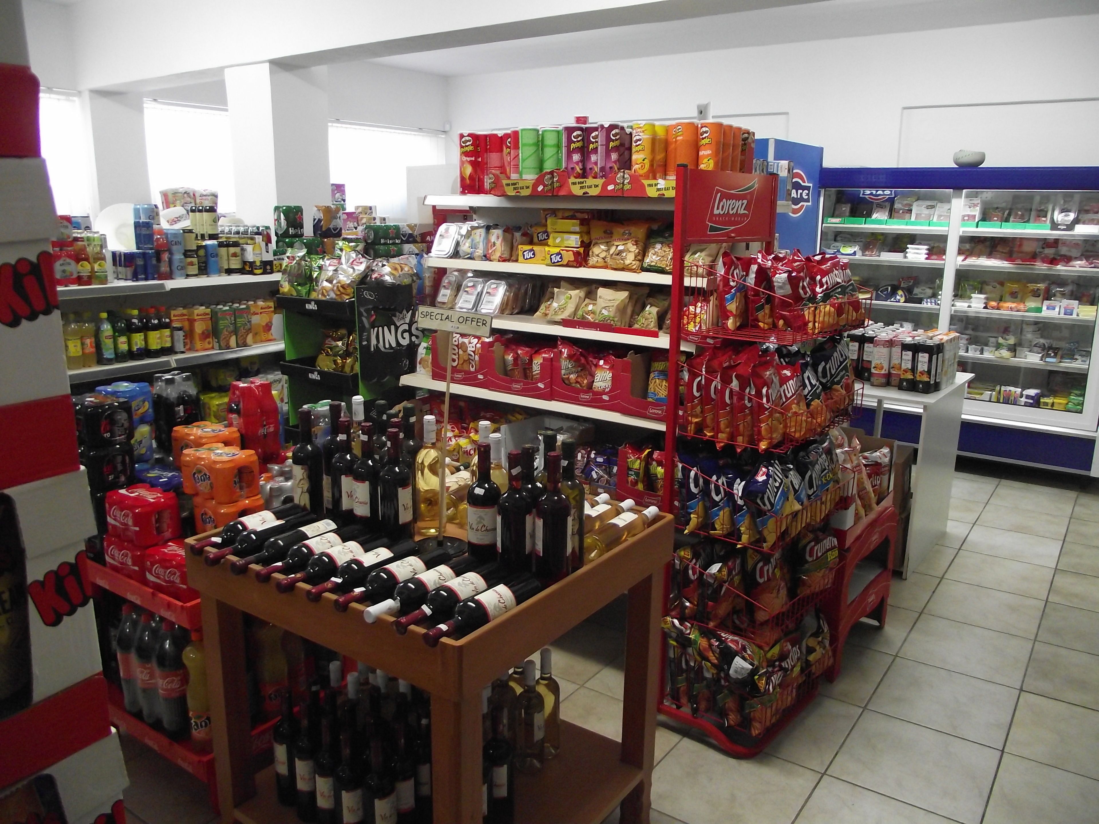 Un supermercado con estantes llenos de productos variados, como bocadillos, bebidas y artículos del hogar.