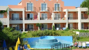 A multi-story hotel with balconies, a swimming pool, and outdoor seating areas.