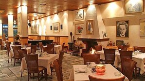 A restaurant with wooden ceiling, tables with white tablecloths, and framed pictures on the walls. - Iniohos Hotel Restaurant (Delphi)