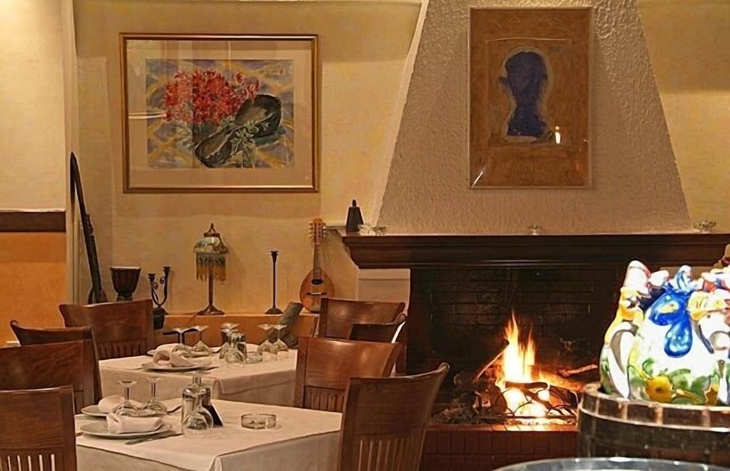 A dining area with a fireplace, framed artwork, and a table set for a meal.