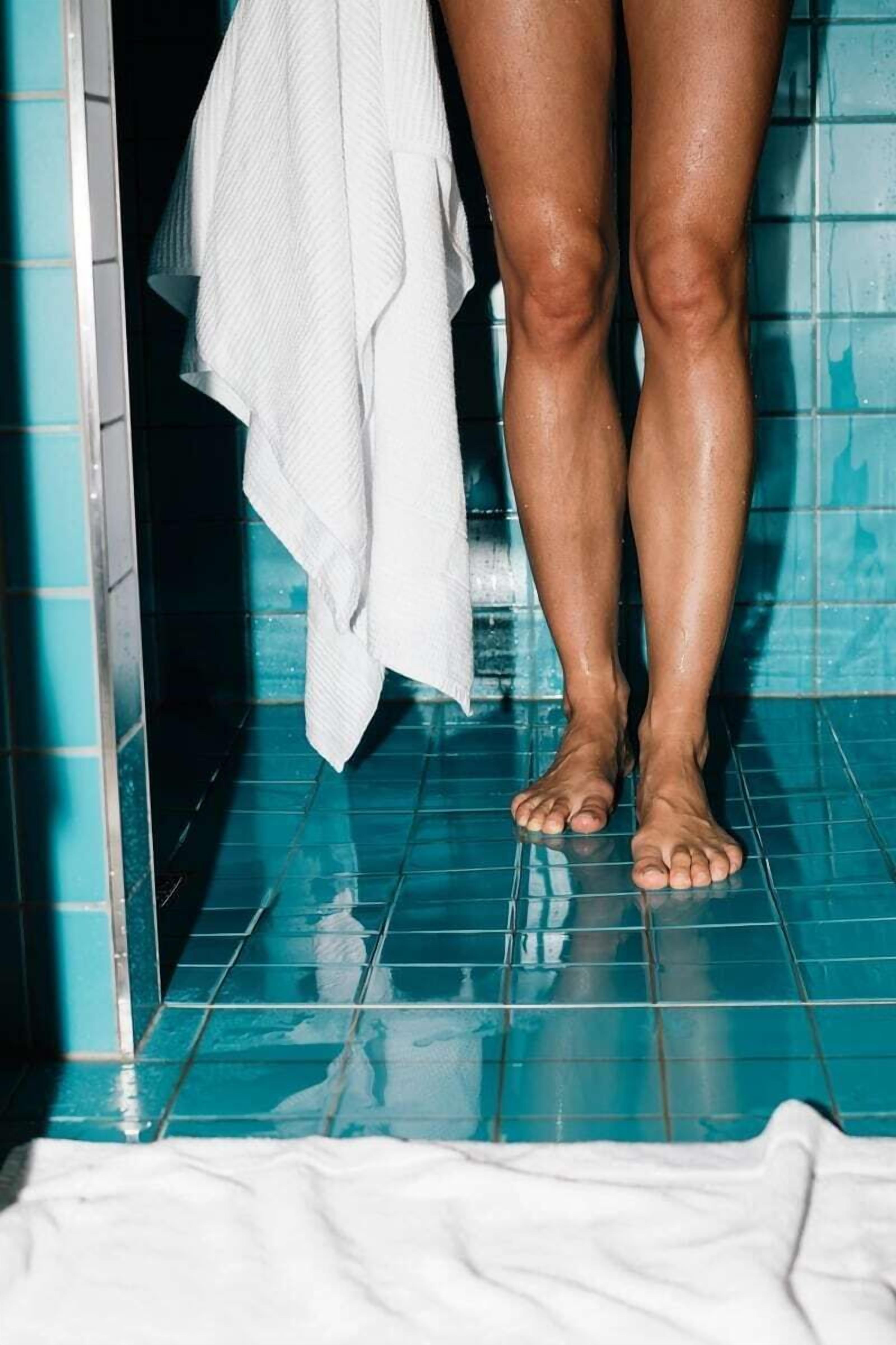 A bathroom with blue tiles and a white towel hanging on the wall.