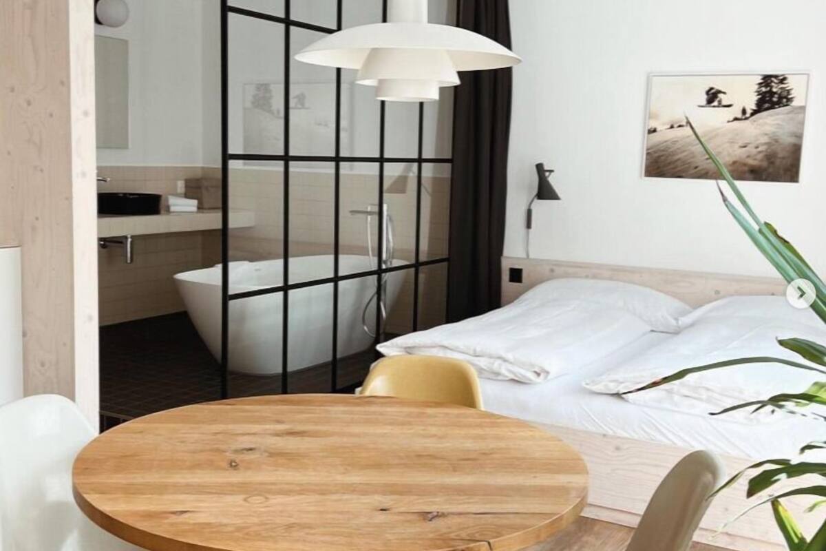 A modern bedroom with a bed, a wooden table, and a chair.