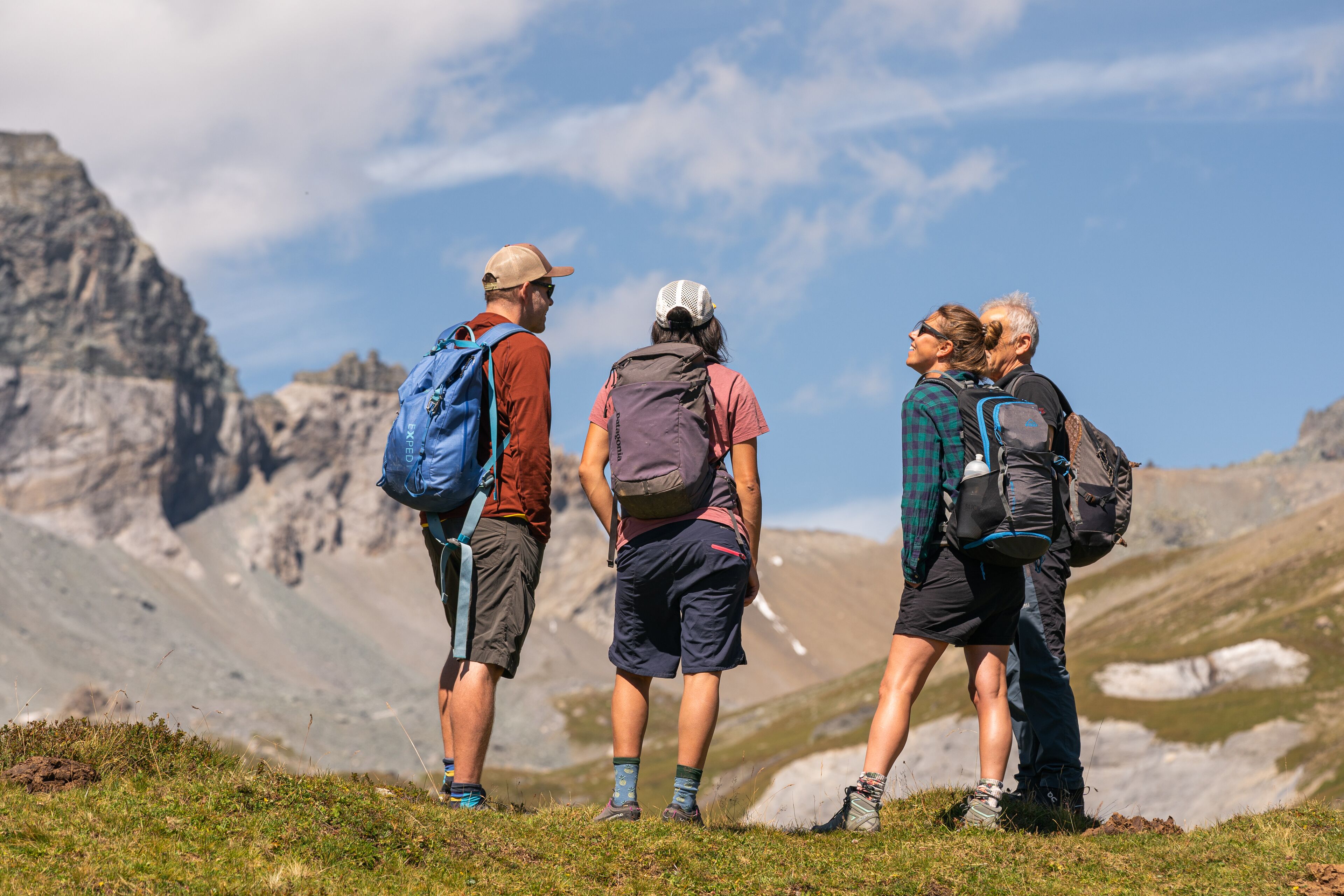 A group of hikers on a mountain trail with rocky terrain and sparse vegetation.
