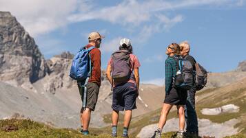 A group of hikers on a mountain trail with rocky terrain and sparse vegetation.