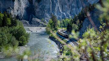 Un río con un tren sobre un puente, rodeado de acantilados rocosos y vegetación.