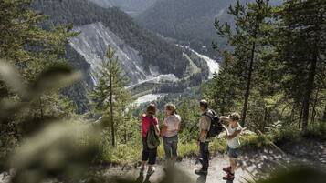 Eine Gruppe von Menschen steht auf einem Bergpfad mit Blick auf ein Tal und einen Fluss.