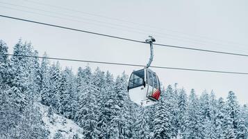 A cable car moving over a snowy forest.