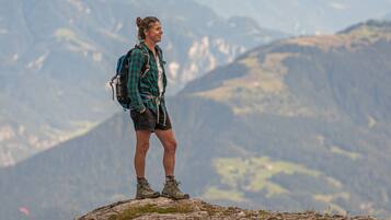A person standing on a rocky outcrop with a mountainous landscape in the background.