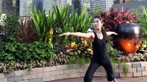 Une personne effectue une posture de yoga sur un tapis violet, dans un cadre extérieur, avec une vue sur la ville en arrière-plan.