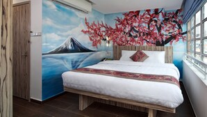 Une chambre avec un lit, une fresque murale représentant une montagne et des fleurs de cerisier, une fenêtre avec vue et un appareil de climatisation.